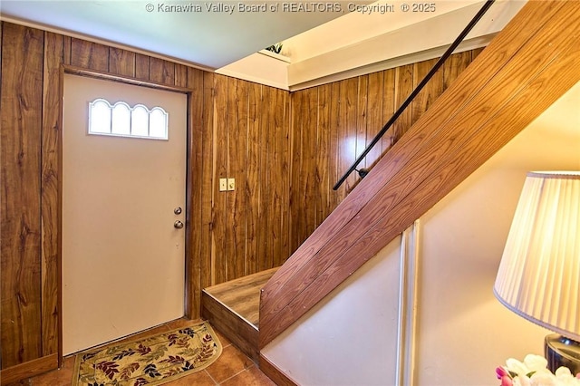 tiled foyer entrance featuring wood walls