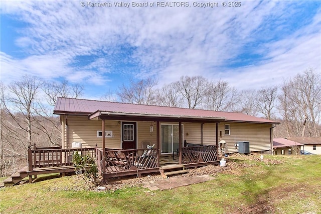 rear view of property featuring a wooden deck, metal roof, central AC, and a yard