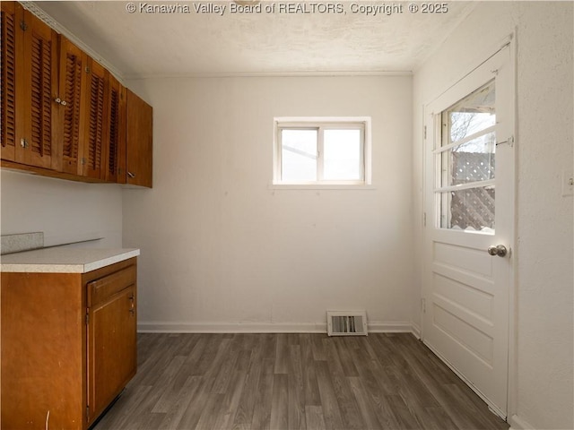 unfurnished dining area featuring dark wood-style flooring, visible vents, and a healthy amount of sunlight