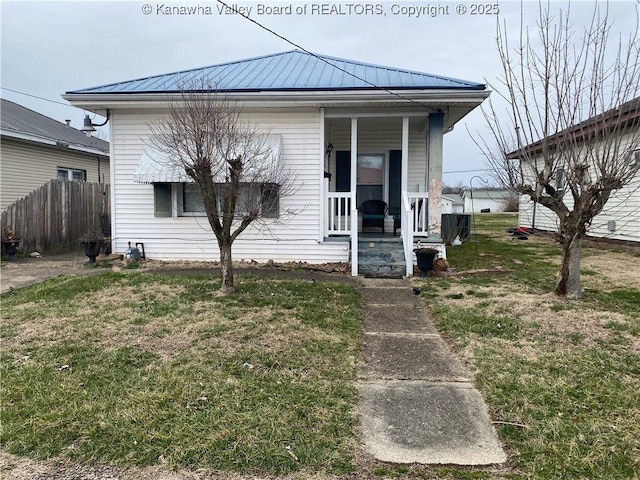 view of front of home with a porch, metal roof, a front lawn, and fence