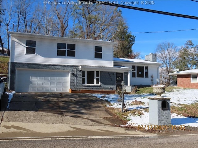 tri-level home with a garage, driveway, brick siding, and a chimney