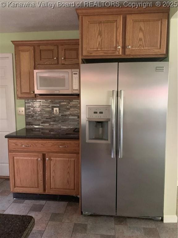 kitchen featuring tasteful backsplash, built in microwave, brown cabinetry, and stainless steel fridge with ice dispenser