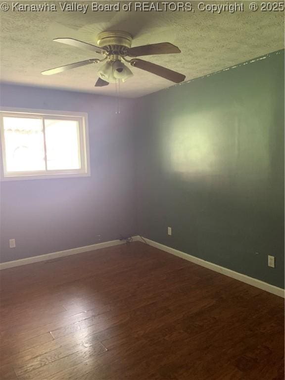 spare room featuring dark wood finished floors, a textured ceiling, and baseboards