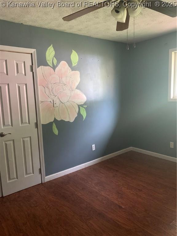 empty room featuring a textured ceiling, wood finished floors, a ceiling fan, and baseboards