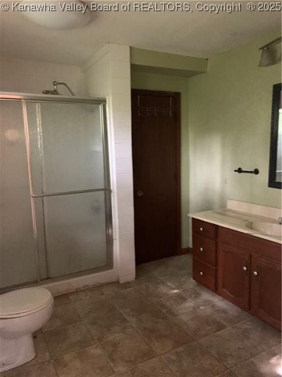 bathroom featuring toilet, a shower stall, and vanity