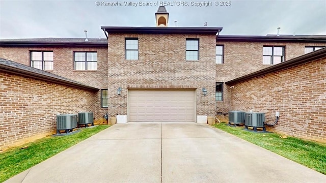 rear view of property featuring an attached garage, cooling unit, and brick siding