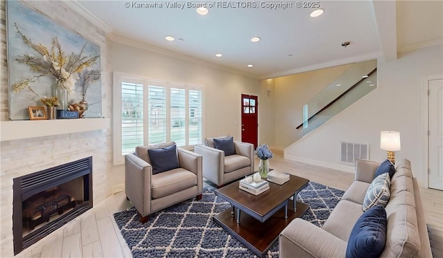 living area featuring crown molding, a fireplace, recessed lighting, visible vents, and stairs