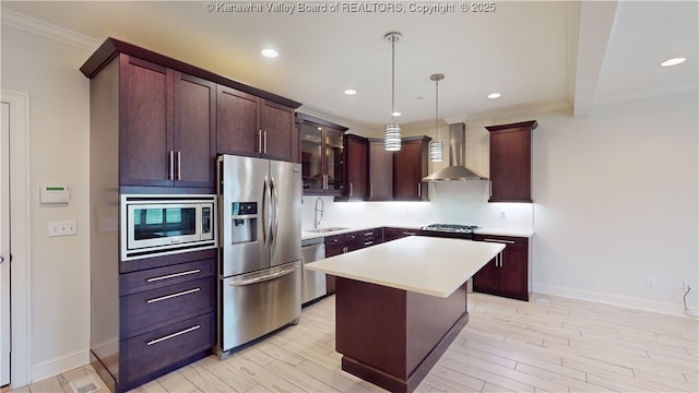 kitchen with wall chimney exhaust hood, appliances with stainless steel finishes, light countertops, light wood-type flooring, and a sink