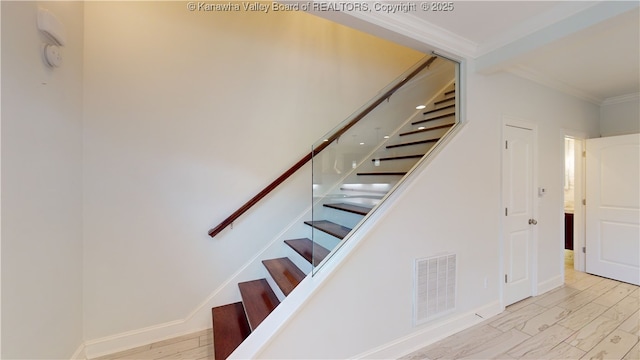 stairs with visible vents, crown molding, baseboards, and wood finished floors