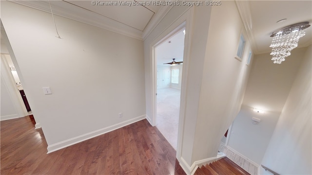 hall with attic access, baseboards, ornamental molding, wood finished floors, and a chandelier