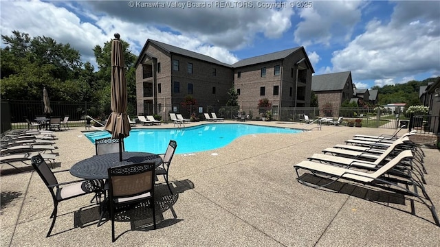 pool with a patio area and fence