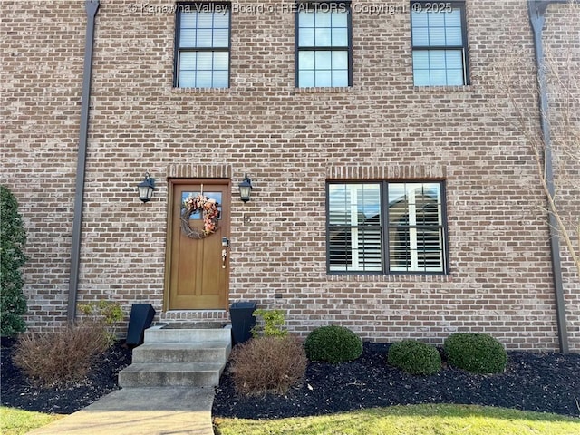 view of exterior entry featuring brick siding