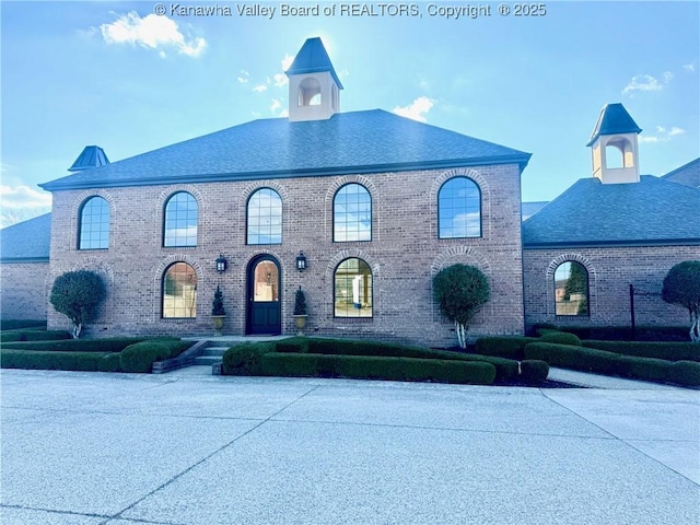 view of front of property with a shingled roof and brick siding