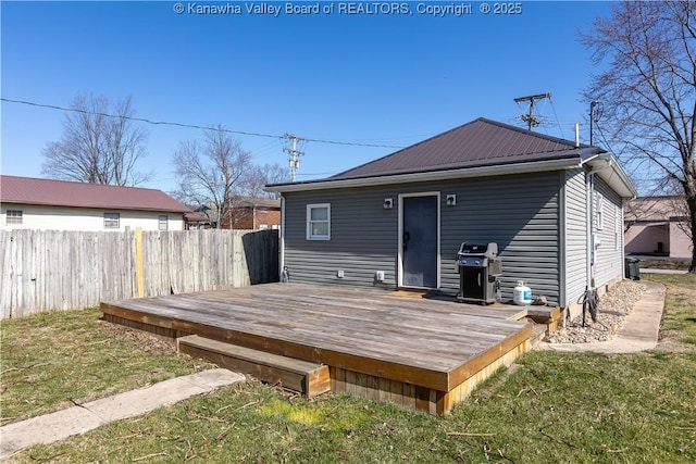 rear view of property with fence, metal roof, a lawn, and a wooden deck