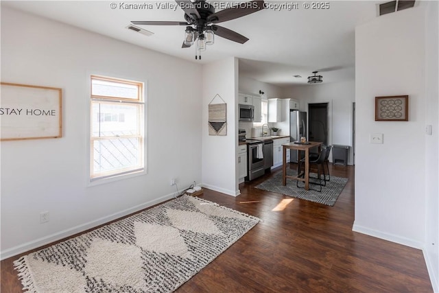 interior space featuring dark wood-style floors, visible vents, baseboards, and a ceiling fan