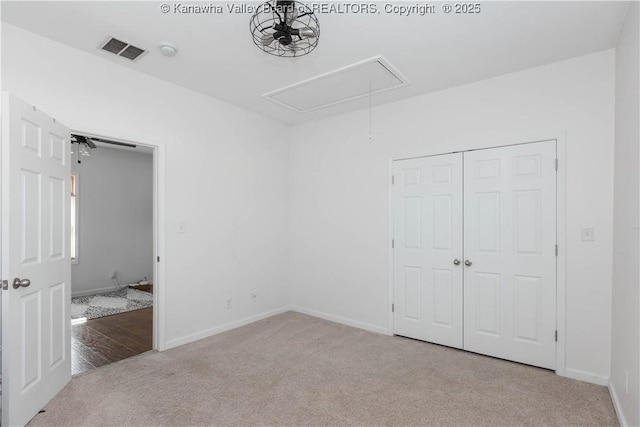 unfurnished bedroom with carpet, attic access, visible vents, and baseboards