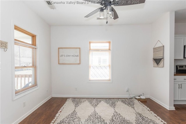 spare room featuring ceiling fan, baseboards, and dark wood-style flooring