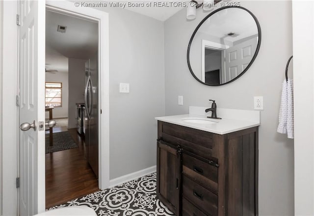 bathroom featuring visible vents, vanity, baseboards, and wood finished floors