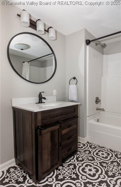 bathroom featuring tile patterned flooring, tub / shower combination, vanity, and baseboards