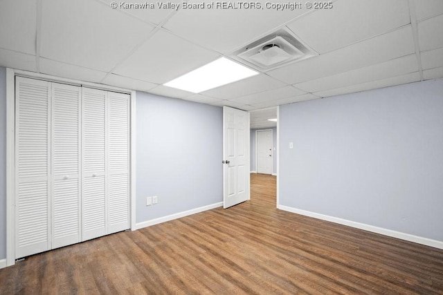 finished basement featuring wood finished floors, visible vents, a drop ceiling, and baseboards