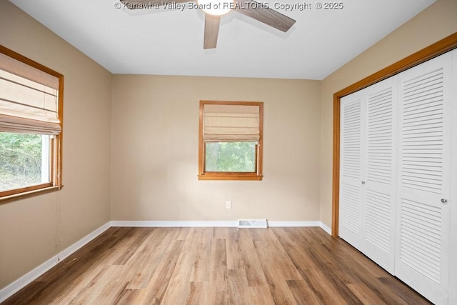 unfurnished bedroom with a closet, visible vents, baseboards, and wood finished floors