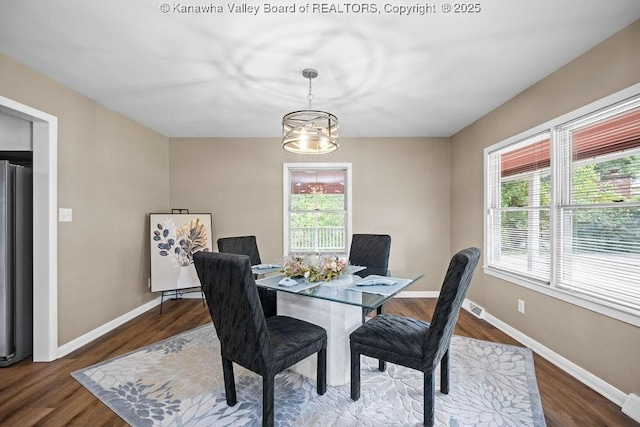 dining area featuring a notable chandelier, visible vents, baseboards, and wood finished floors