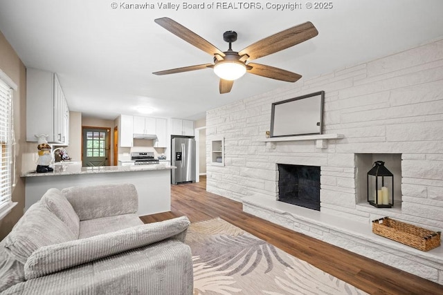 living room with a ceiling fan, wood finished floors, and a fireplace