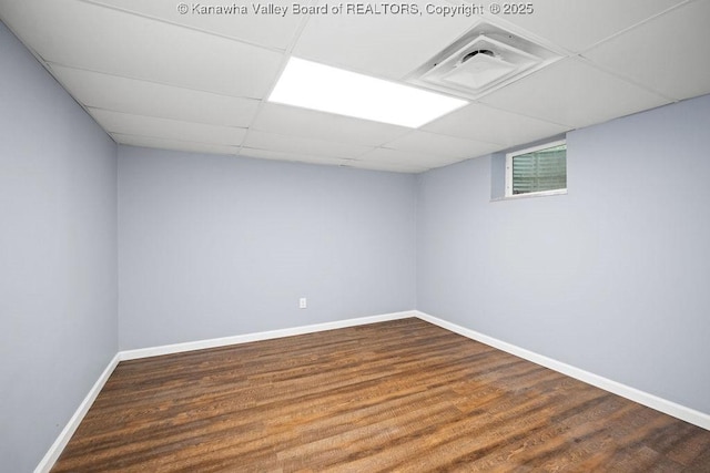 finished basement featuring visible vents, a drop ceiling, baseboards, and wood finished floors