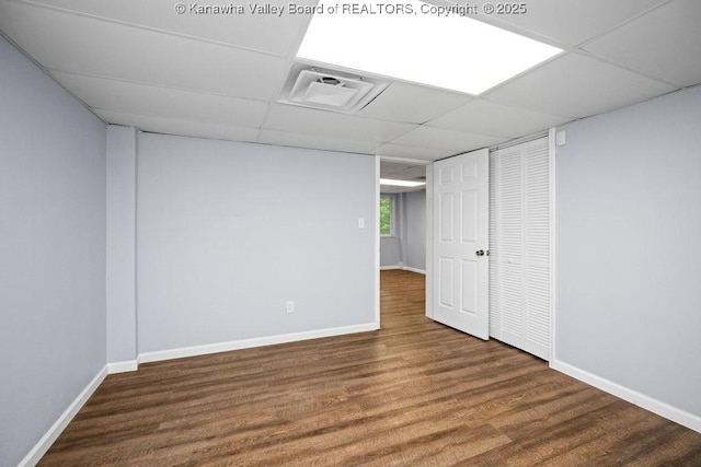 basement with visible vents, wood finished floors, baseboards, and a paneled ceiling