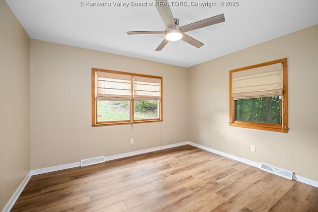 spare room with a ceiling fan, wood finished floors, visible vents, and baseboards