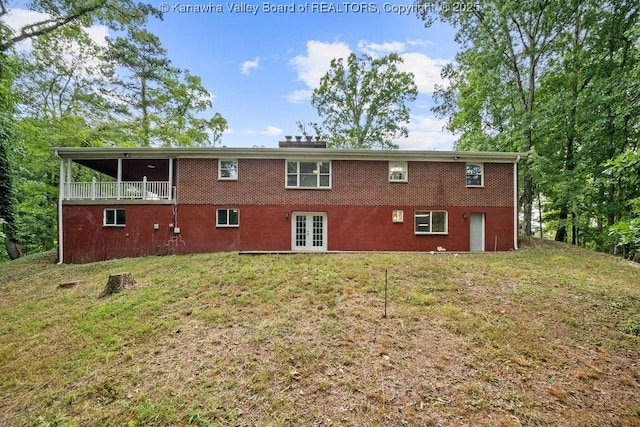 rear view of house with a lawn, brick siding, and french doors