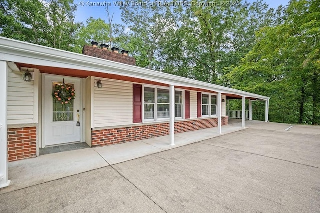 view of front of house featuring brick siding, covered porch, and a chimney