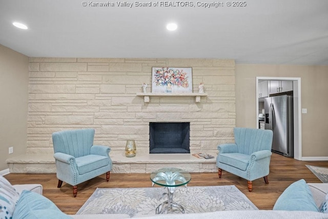 living area with a stone fireplace, recessed lighting, wood finished floors, and baseboards