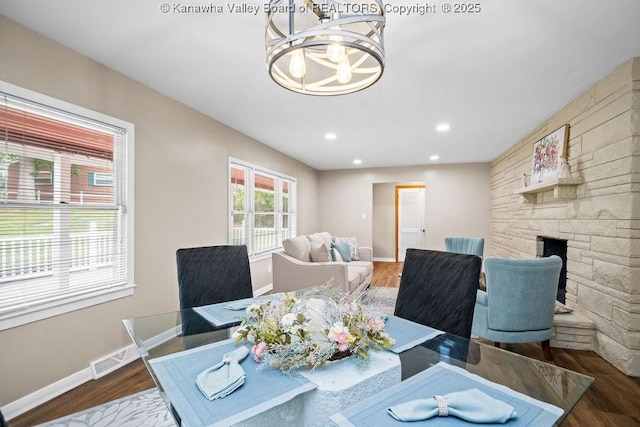 dining space featuring visible vents, baseboards, a stone fireplace, recessed lighting, and wood finished floors