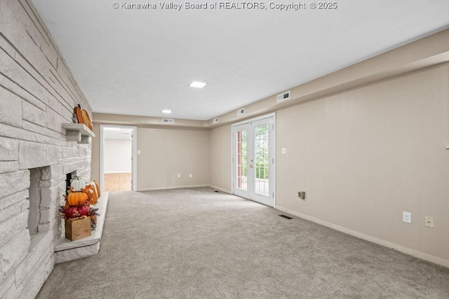 unfurnished living room featuring french doors, a fireplace, visible vents, and carpet floors