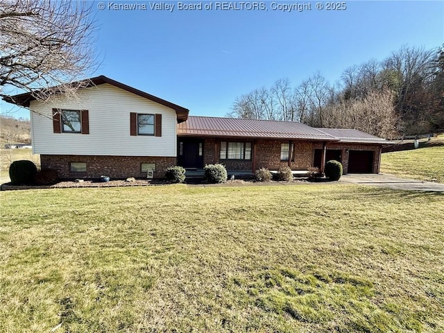 tri-level home with an attached garage, metal roof, and a front yard