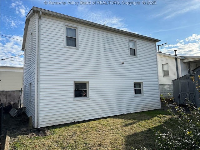 back of house featuring a yard, a storage unit, and an outdoor structure