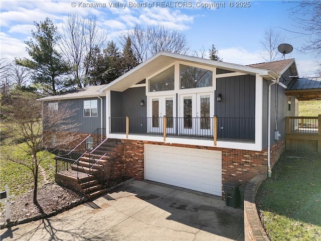 view of front of house with concrete driveway, a garage, french doors, and brick siding