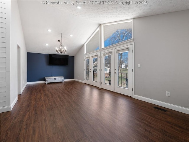 unfurnished living room featuring visible vents, baseboards, wood finished floors, a notable chandelier, and a textured ceiling