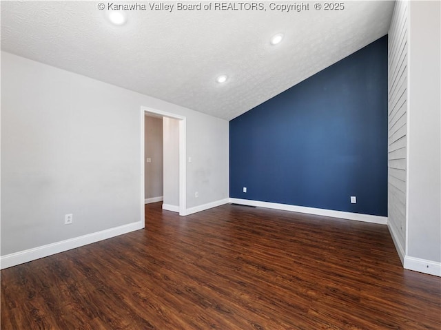 empty room featuring lofted ceiling, a textured ceiling, dark wood-style floors, recessed lighting, and baseboards