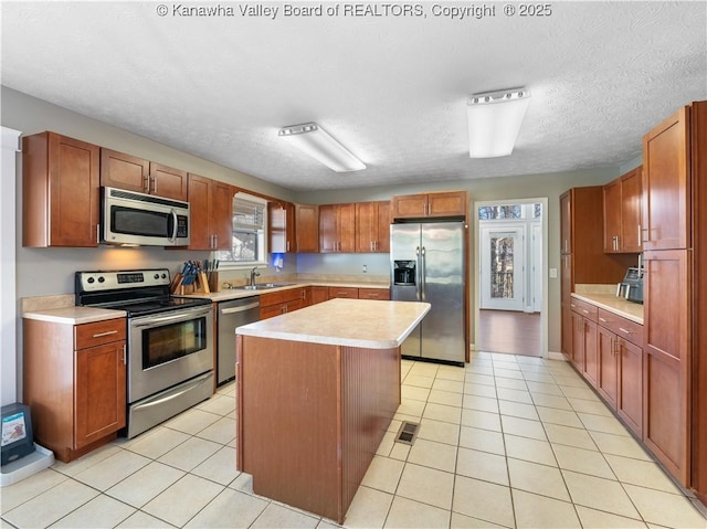 kitchen featuring light tile patterned floors, appliances with stainless steel finishes, a kitchen island, and light countertops