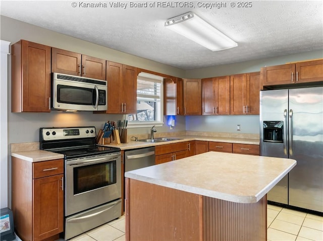 kitchen with a sink, light countertops, a textured ceiling, and stainless steel appliances