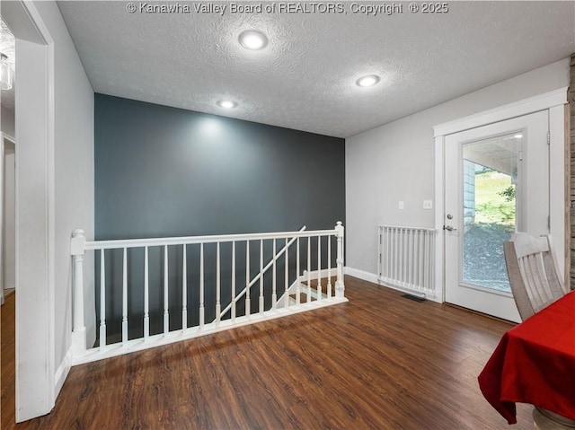 empty room with visible vents, a textured ceiling, and wood finished floors