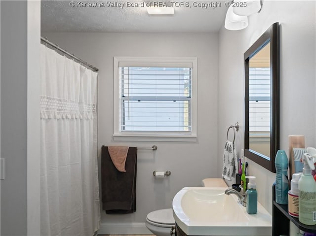 full bath with baseboards, toilet, a healthy amount of sunlight, and vanity