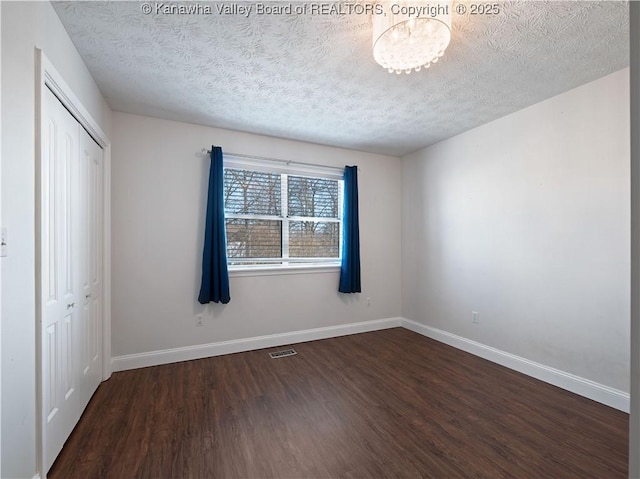 unfurnished bedroom featuring visible vents, a textured ceiling, wood finished floors, a closet, and baseboards