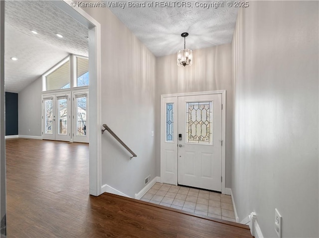 foyer featuring an inviting chandelier, a textured ceiling, baseboards, and wood finished floors