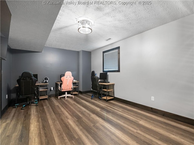 office area featuring visible vents, baseboards, a textured ceiling, and wood finished floors