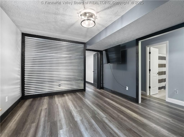 empty room with wood finished floors, baseboards, and a textured ceiling