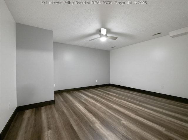 spare room featuring visible vents, baseboards, ceiling fan, dark wood-style floors, and a textured ceiling