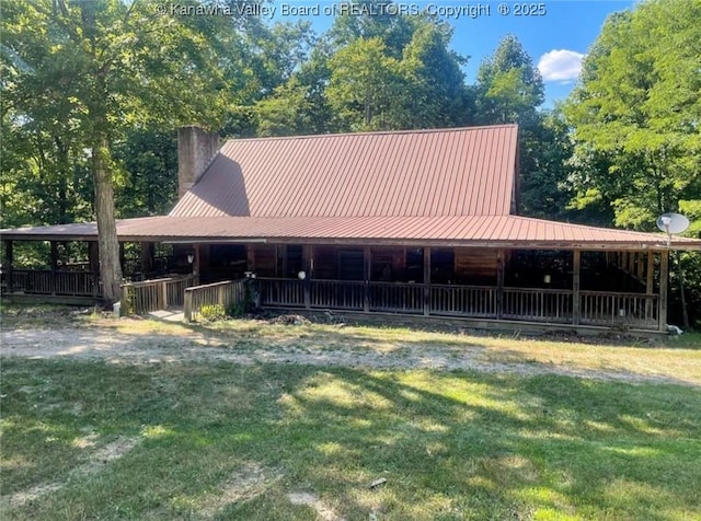 farmhouse with a front yard, metal roof, and a chimney